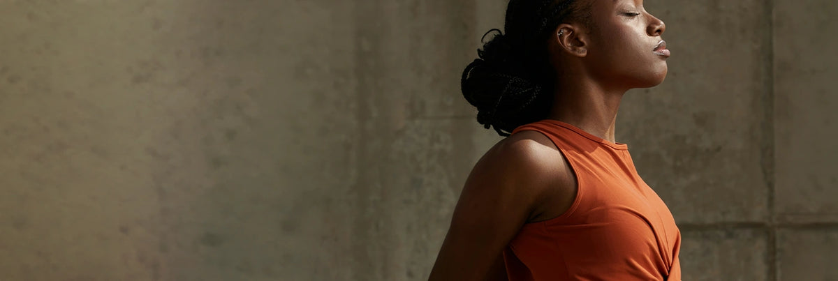 A woman in profile standing against a textured beige wall.