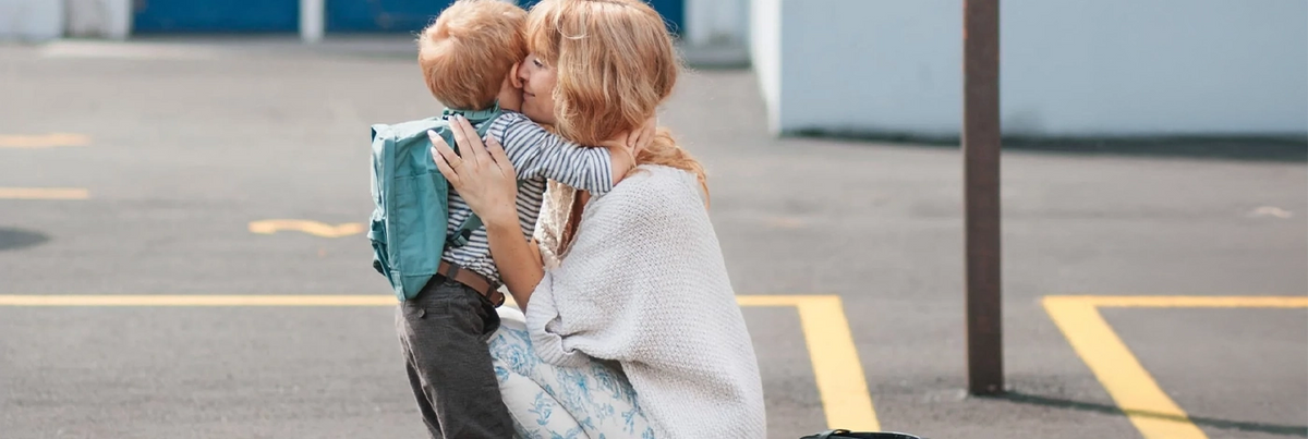 A woman hugs a young boy after school.